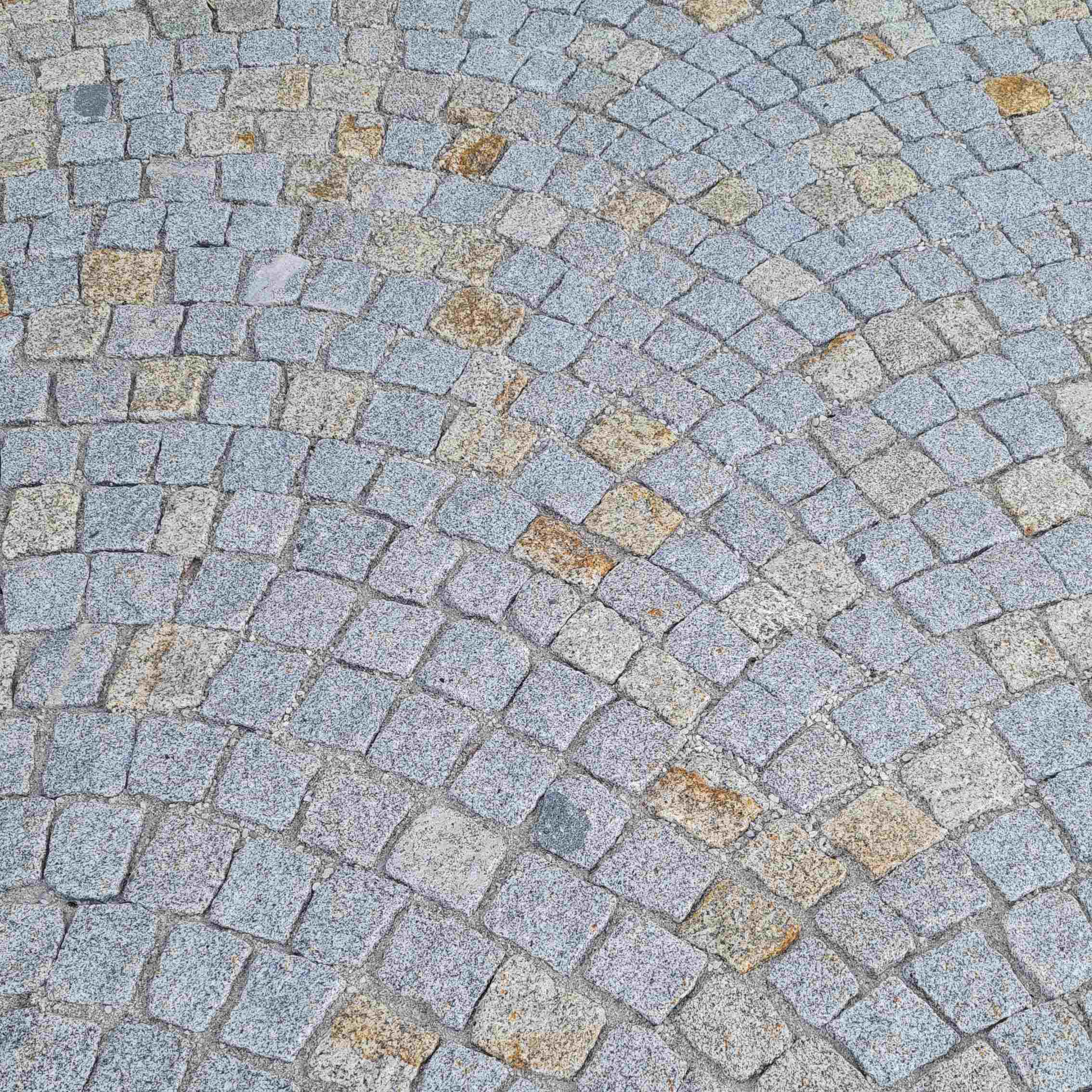 Natursteinboden mit unregelmäßig geformten Steinen in warmen Erdtönen, darunter Beige, Hellbraun und rötliche Nuancen. Die Steine haben eine raue, rustikale Oberfläche, die ihre natürliche Struktur und Maserung hervorhebt. Die Fugen sind deutlich sichtbar, was dem Boden eine organische, traditionelle Optik verleiht. Dieser Bodenbelag ist ideal für Außenbereiche wie Gartenwege, Terrassen oder Einfahrten geeignet.