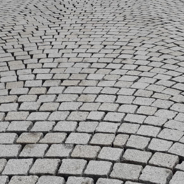 Nahaufnahme eines gepflasterten Natursteinbodens mit rechteckigen Steinen. Die Steine sind überwiegend in warmen Beige- und Sandtönen gehalten, mit leichten Variationen in Helligkeit und Textur. Die Fugen zwischen den Steinen sind schmal und gleichmäßig, was dem Bodenbelag ein ordentliches und harmonisches Aussehen verleiht.