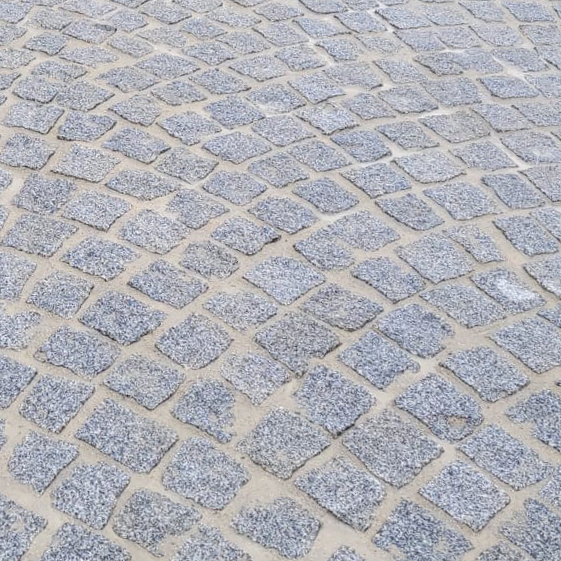 Natursteinboden aus unterschiedlich großen, rechteckigen und quadratischen Steinen in verschiedenen warmen Beige- und Brauntönen. Die Steine haben eine leicht strukturierte Oberfläche, die ihre natürlichen Farbverläufe und Muster betont. Die gleichmäßige Verlegung der Steine sorgt für ein geordnetes und dennoch natürlich wirkendes Erscheinungsbild. Der Boden ist ideal für den Einsatz in Außenbereichen wie Terrassen oder Gehwegen.