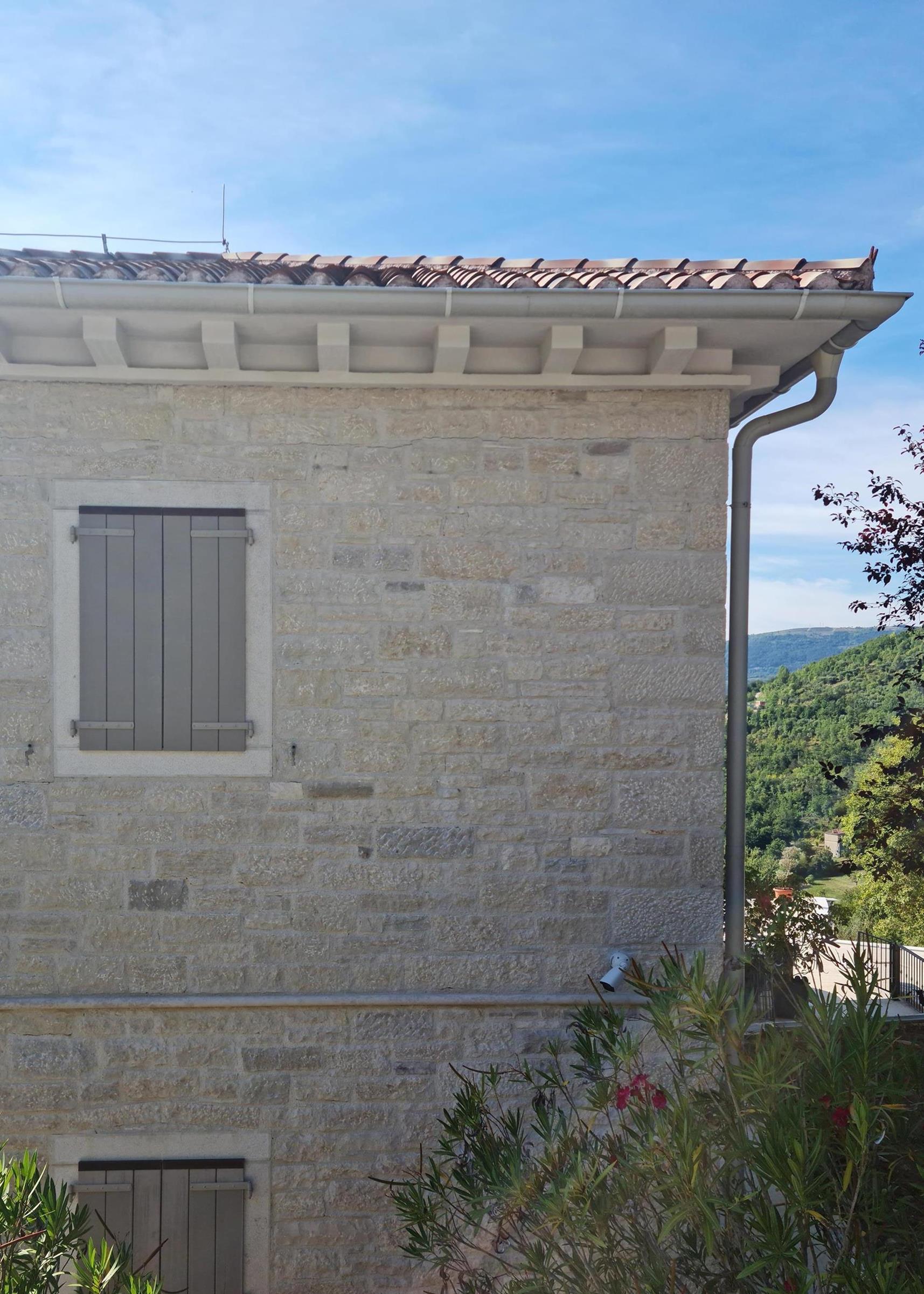 Hauswand verkleidet mit weißem und grauen Naturstein. Istrischer Kalkstein