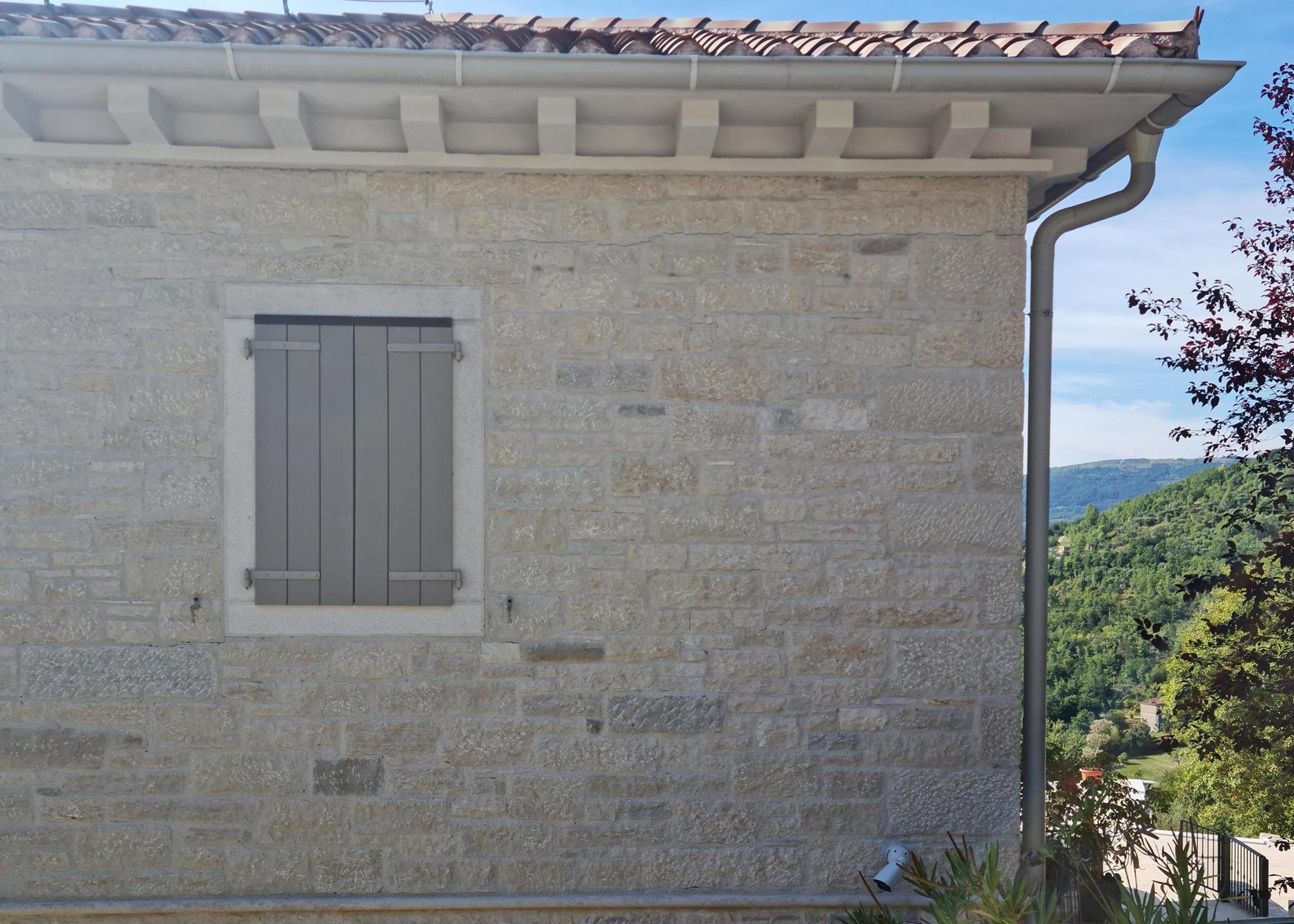 Wandverkleidung von einem Haus aus weiß, grau, gelbem Naturstein