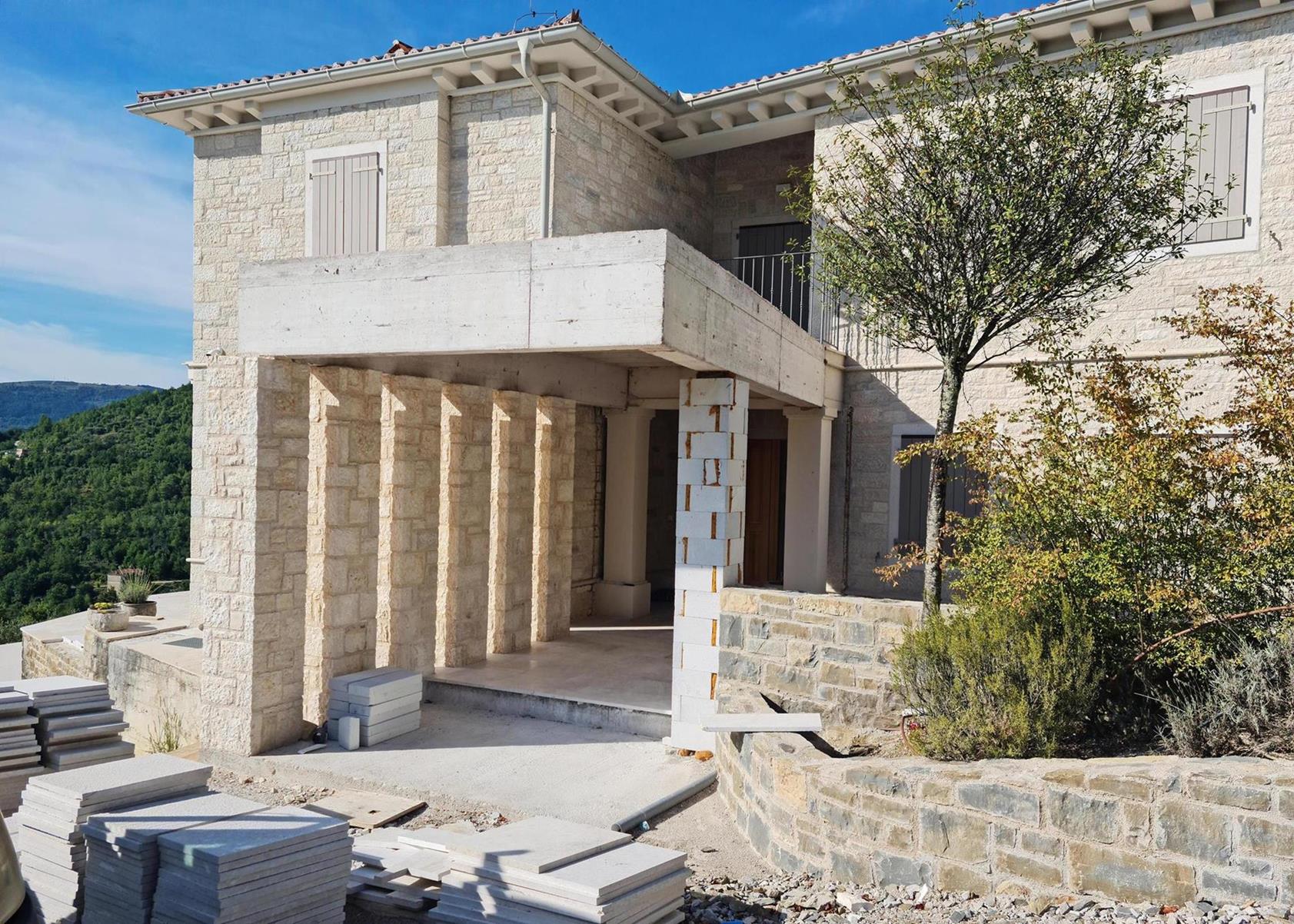 Wandverkleidung von einem Haus aus weiß, grau, gelbem Naturstein mit Säulen